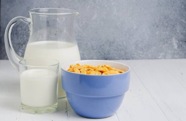 Bardakta mısır gevreği ve süt. Beyaz ahşap masa. Boşluğu kopyala