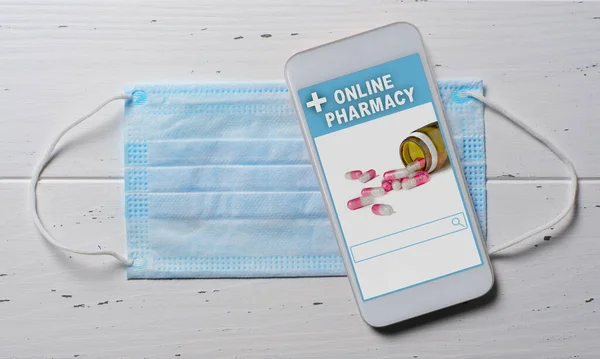 Online pharmacy. Application in smartphone for online ordering of medicines. Medical disposable face mask and the phone on a white background. The concept of convenient choice of medicines