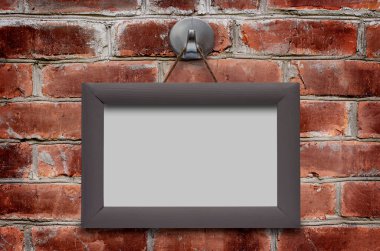 Kahverengi tuğla duvarda ahşap bir çerçeve asılı. Boşluğu kopyala