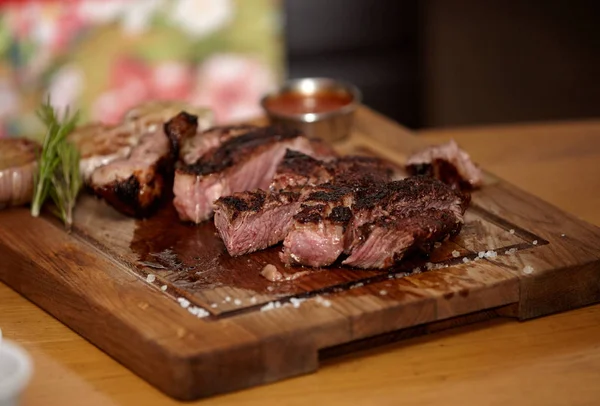 Grilled medium rare steak with coarse salt and rosemary on a woo