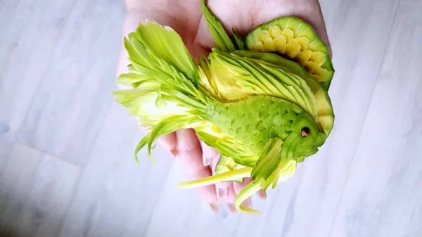 Avocado carving - Magic green fish cut out of avocado in the han