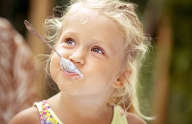 Sevimli kız çocuk bir co lezzetli bir dondurma ile bir kaşık yalar