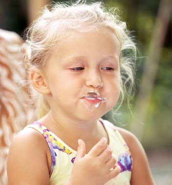 Sevimli küçük kız bir c lezzetli bir dondurma ile bir kaşık yalar