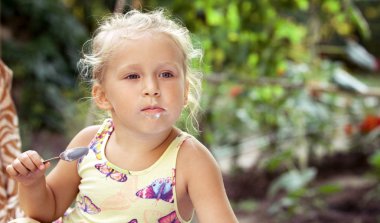 Sevimli küçük kız bir c lezzetli bir dondurma ile bir kaşık yalar