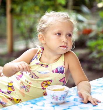 Sevimli küçük kız bir c lezzetli bir dondurma ile bir kaşık yalar