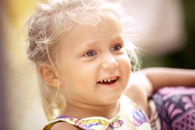 Güzel küçük kız sarışın renkli bir arka plan üzerinde gülümsüyor