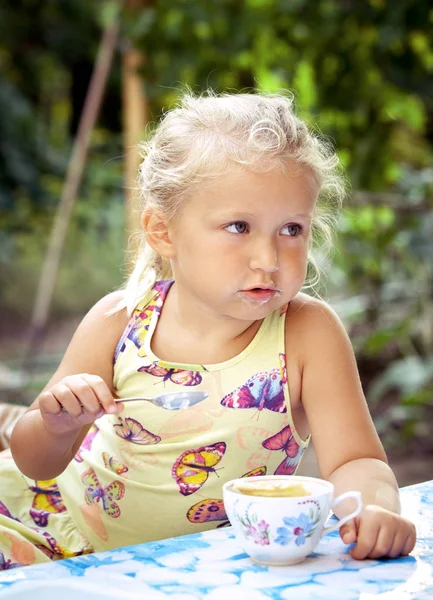 Sevimli küçük kız bir c lezzetli bir dondurma ile bir kaşık yalar