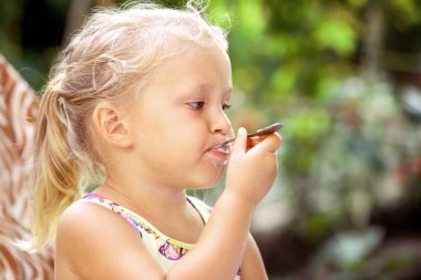 Sevimli küçük kız bir c lezzetli bir dondurma ile bir kaşık yalar