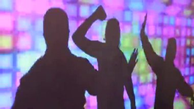 Bir parti sırasında bir gece kulübünde renkli bir ekranda dans kadın ve erkek silueti.