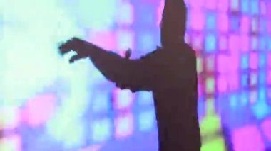 Bir parti sırasında bir gece kulübünde renkli bir ekranda dans kadın ve erkek silueti.