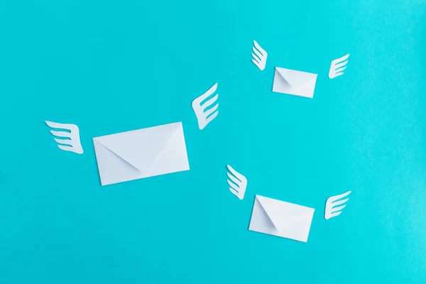 Three flying letters from paper, message, mail, sms, blue background, wings, minimalism