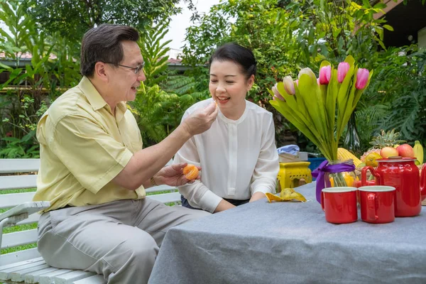 Asian elderly couples are taking care of each other by stripping oranges to eat. Family concept, couples concept