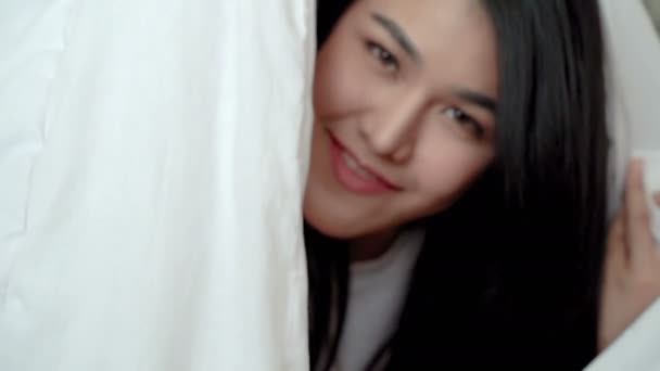 微笑着的开朗的女人从家里的床毯子下偷看出来 — 图库视频影像