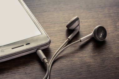 ahşap zemin üzerinde mobil ve kulaklıklar.