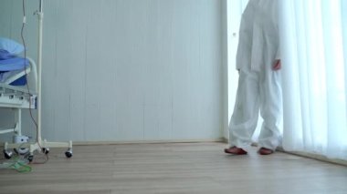 Salgın durumunda, Asyalı bir kadın doktor maskesini ve başlığını çıkararak yere oturdu. Doktor çok yoruldu, çok çalıştıktan sonra yoruldu..