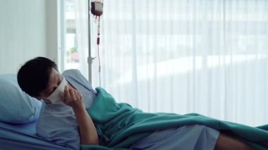 Covid 19 'lu yaşlı Asyalı hastalar, bir hastane yatağında akciğer enfeksiyonu nedeniyle öksürüyor, hayal kırıklığına uğramış ve umutsuz bir şekilde yatıyor.