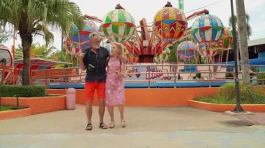 Yaşlı çiftler hip-hop kostümü giyer ve lunaparkta dans edip eğlenirler..