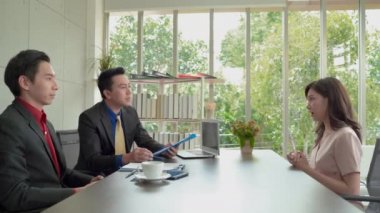 Asyalı bir kadın bir iş görüşmesi yapıyor, mülakatçıyla el sıkışıyor ve iş bulmayı bekliyor..