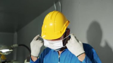 COVID 19 enfeksiyonunu önlemek için yüz maskesi takan genç Asyalı ustabaşı.