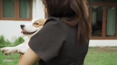 Güzel bir Asyalı kadının Galli bir Corgi köpeğini tutarken çekilmiş bir turna görüntüsü..