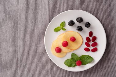 Plaka gri bir arka plan üzerinde çilek ile. Çocuklar için yaratıcı kahvaltı fikirler