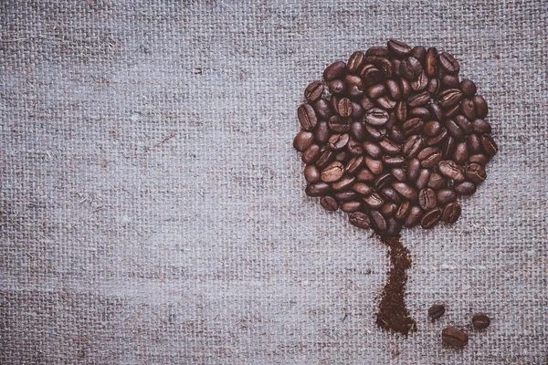 Coffee tree made of coffee beans on burlap rustic rough simple beautiful. Brown roasted beans on brown background.