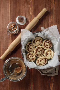 Rulo tarçın. Baharat ve parşömen kağıt üzerine doldurma kakao ile taze pişmiş tarçınlı çörek. Üstten Görünüm. Tatlı ev yapımı pasta Noel pişirme. Yakın çekim. Kanelbule - İsveç tatlı.