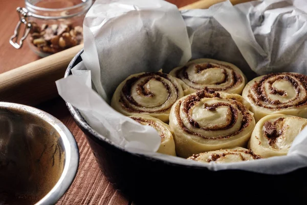 Rulo tarçın. Baharat ve parşömen kağıt üzerine doldurma kakao ile taze pişmiş tarçınlı çörek. Üstten Görünüm. Tatlı ev yapımı pasta Noel pişirme. Yakın çekim. Kanelbule - İsveç tatlı.