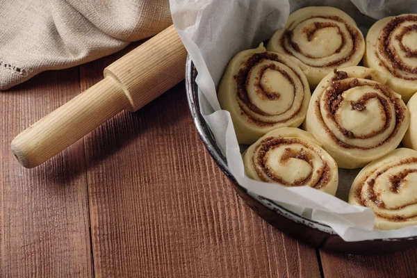 Cinnamon rolls. Freshly baked cinnamon buns with spices and cocoa filling on parchment paper. Top view. Sweet Homemade Pastry christmas baking. Close-up. Kanelbule - swedish dessert.