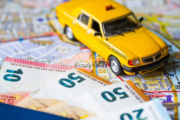 Euro money banknotes bills, passport, toy car and funny sunglasses on copy space background, top view. Car rental concept - car key and money on the road map