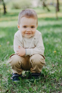 Tahta köprüde uzanan mutlu çocuğun açık hava portresi ve gülümseyen yüzüyle kameraya bakmak vahşi yaşam parkında oynayan aktif çocuk, güneşli yaz gününde doğa koruma alanında macera yaşayan çocuk.