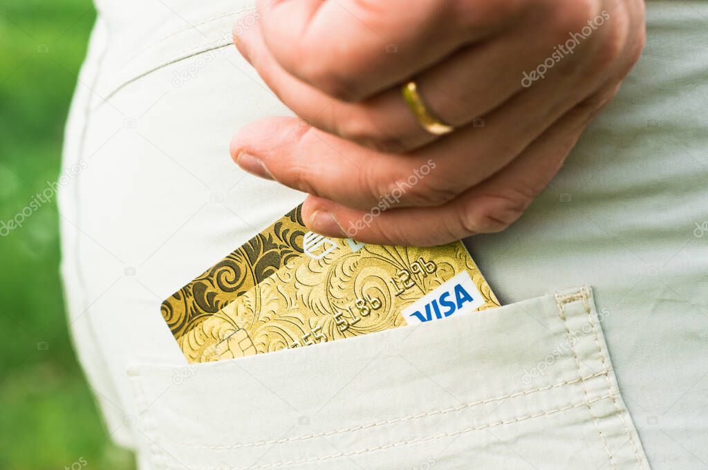 Cropped view of girl putting credit card into pocket, isolated on pink