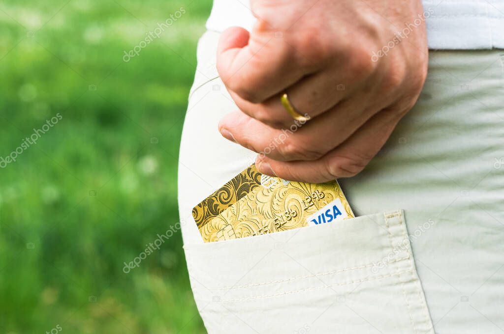 Cropped view of girl putting credit card into pocket, isolated on pink