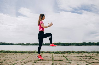 Genç, güzel bir atlet kız koşuyor. Güzel kız sporcu koşu yapıyor. Sabah koşusu. sağlıklı spor yaşam tarzı konsepti. Gri kazaklı ve siyah taytlı genç kız spor için içeri giriyor.
