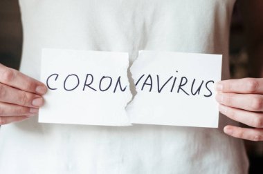 Kadının elinde COVID 19 posteri var. Beyaz harflerle yazılmış son el yazısı. Coronovirus COVID 19 konsepti