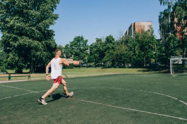 Sporcu idmandan önce ısınmak için hamleler yapar. Erkek vücut geliştirici spor sahasında eğitim görüyor. Tam stadyum planı