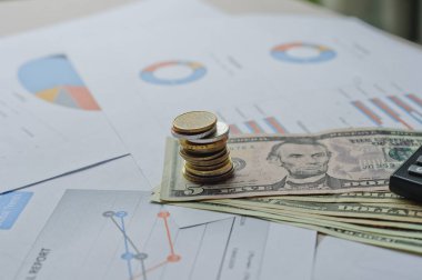 Dolarlar, hesap makinesi, loupe, kalemler ve defterler evrakların üzerinde. Ofis malzemeleri masanın üzerinde. Ofis malzemeleri mali beyanlarda yatıyor. 