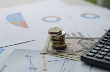 Dolarlar, hesap makinesi, loupe, kalemler ve defterler evrakların üzerinde. Ofis malzemeleri masanın üzerinde. Ofis malzemeleri mali beyanlarda yatıyor. 