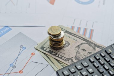 Dolarlar, hesap makinesi, loupe, kalemler ve defterler evrakların üzerinde. Ofis malzemeleri masanın üzerinde. Ofis malzemeleri mali beyanlarda yatıyor. 