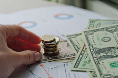Dolarlar, hesap makinesi, loupe, kalemler ve defterler evrakların üzerinde. Ofis malzemeleri masanın üzerinde. Ofis malzemeleri mali beyanlarda yatıyor. 