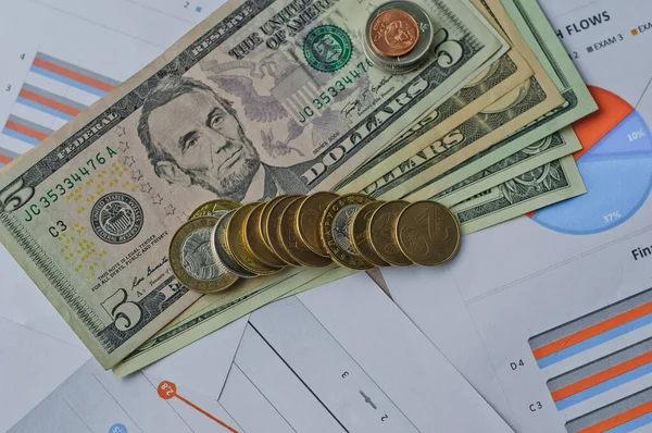 Dolarlar, hesap makinesi, loupe, kalemler ve defterler evrakların üzerinde. Ofis malzemeleri masanın üzerinde. Ofis malzemeleri mali beyanlarda yatıyor. 