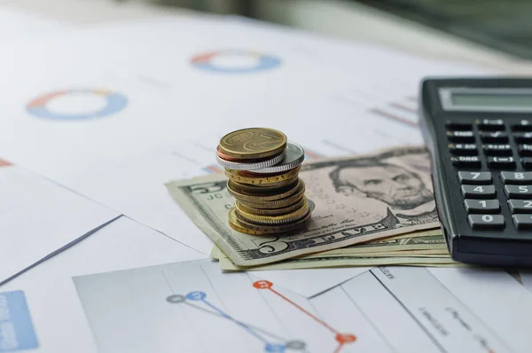 Dolarlar, hesap makinesi, loupe, kalemler ve defterler evrakların üzerinde. Ofis malzemeleri masanın üzerinde. Ofis malzemeleri mali beyanlarda yatıyor. 