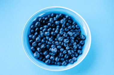 Ahşap bir masada kasede yaban mersini. Menekşe yüzeyinde en üst tabak ve yaban mersini manzarası