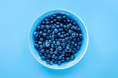 Ahşap bir masada kasede yaban mersini. Menekşe yüzeyinde en üst tabak ve yaban mersini manzarası