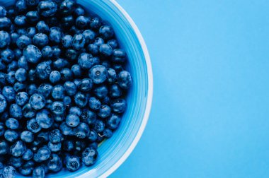 Ahşap bir masada kasede yaban mersini. Menekşe yüzeyinde en üst tabak ve yaban mersini manzarası