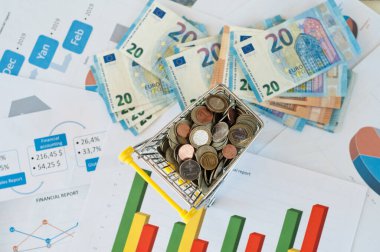 Grafikleri ve ekonomik durumu olan dokümanlarda avroluk bozuk para dolu bir araba.