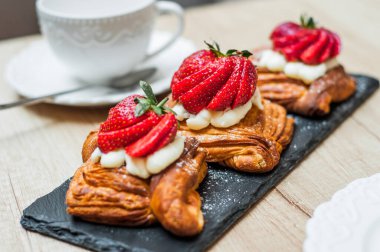 Böğürtlenli ve ahşap arka planda şeker tozlu lezzetli puf börekleri.
