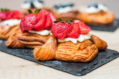 Böğürtlenli ve ahşap arka planda şeker tozlu lezzetli puf börekleri.