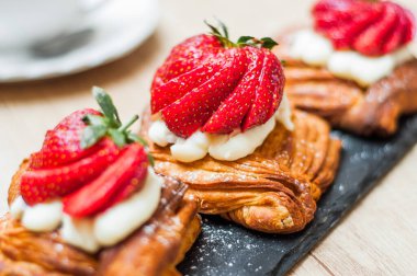 Böğürtlenli ve ahşap arka planda şeker tozlu lezzetli puf börekleri.