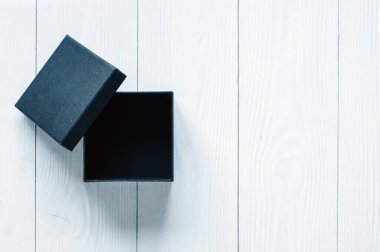 Beyaz ahşap arka planda siyah hediye kutusu